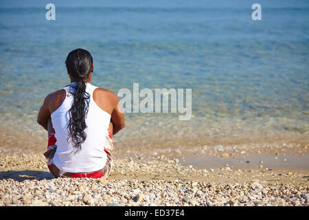 Back of young man sitting on the sea coast Stock Photo