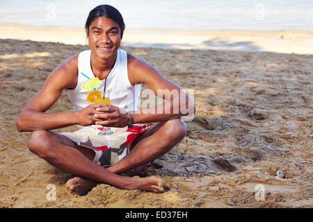 Happy Latino man having fresh drink by the seaside Stock Photo