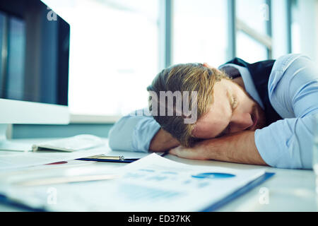 Young tired businessman sleeping by his workplace Stock Photo