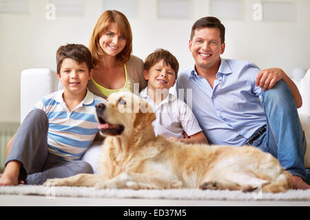 Two lads, their mother, father and dog resting at home Stock Photo