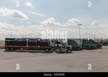 Reels of plastic underground pipe on flatdeck trailer heading for the US oilfields from Canada Stock Photo