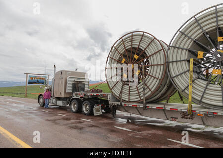 An American Peterbilt 379 semi truck hauling reels of HDPE plastic pipe on a flatbed trailer for the oil industry and fracking sites in the USA Stock Photo