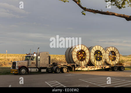 An American Peterbilt 379 semi truck hauling reels of HDPE plastic pipe on a flatbed trailer for the oil industry and fracking sites in the USA Stock Photo