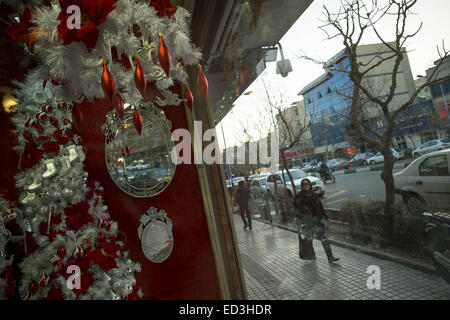 Tehran, Iran. 25th Dec, 2014. December 25, 2014 - Tehran, Iran - An Iranian woman walks past a shop window decorated for the Christian New Year shopping in Tehran's business district. Morteza Nikoubazl/ZUMAPRESS Credit:  Morteza Nikoubazl/ZUMA Wire/Alamy Live News Stock Photo