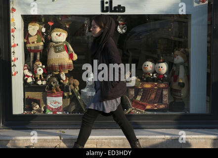 Tehran, Iran. 25th Dec, 2014. December 25, 2014 - Tehran, Iran - An Iranian woman walks past a shop window decorated for the Christian New Year shopping in Tehran's business district. Morteza Nikoubazl/ZUMAPRESS Credit:  Morteza Nikoubazl/ZUMA Wire/Alamy Live News Stock Photo