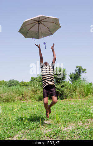 1 rural child boy farm Jumping  holding Umbrella rain season enjoy Stock Photo