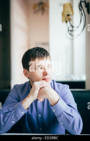 Caucasian Handsome Thinking Man In Blue Shirt Sitting In Cafe Stock Photo