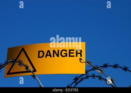 A warning sign on some razor wire Stock Photo