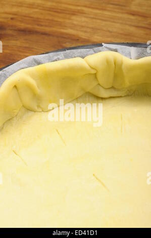 Ready-made puff pastry in pie dish on wooden table Stock Photo