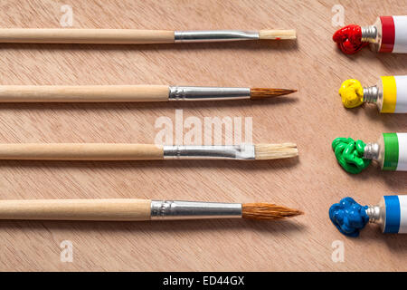 Four different oil paints and paint brushes on a palette Stock Photo