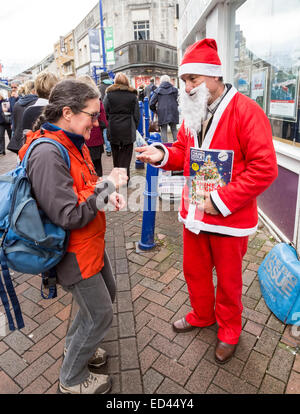 Big Issue seller on street at Christmas, Abergavenny, Wales, UK Stock Photo