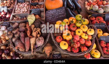 seasonal vegetables in various containers and baskets on a stall pumpkins squashes, root veg tomatoes Stock Photo