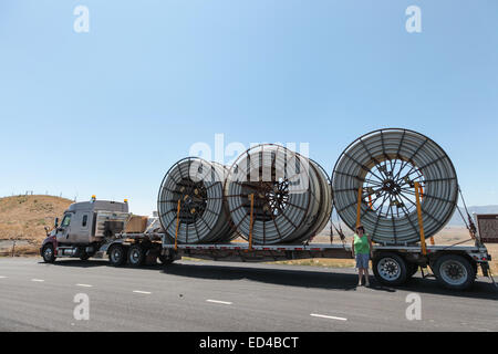 An American semi truck hauling reels of HDPE plastic pipe on a flatbed trailer for the oil industry and fracking sites in the USA Stock Photo