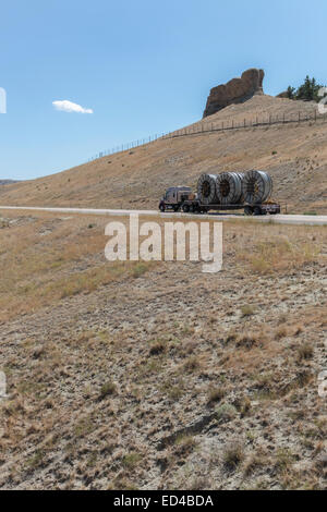 An American semi truck hauling reels of HDPE plastic pipe on a flatbed trailer for the oil industry and fracking sites in the USA Stock Photo