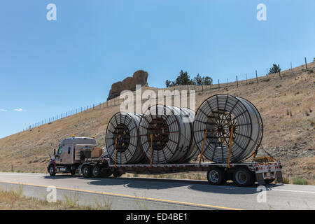 An American semi truck hauling reels of HDPE plastic pipe on a flatbed trailer for the oil industry and fracking sites in the USA Stock Photo