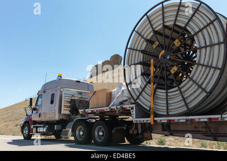 An American semi truck hauling reels of HDPE plastic pipe on a flatbed trailer for the oil industry and fracking sites in the USA Stock Photo