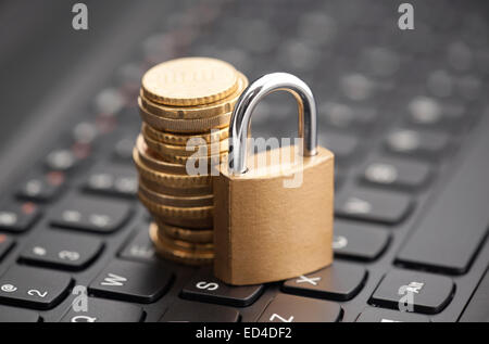 Padlock and coins on laptop keyboard Stock Photo