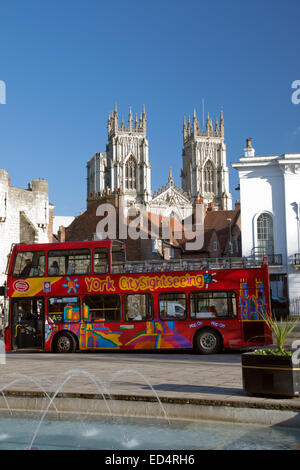 A red double decker sightseeing bus in St Leonards Place York, and York Minster, North Yorkshire, England. Stock Photo