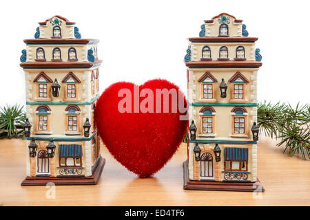 Wonderful Christmas decoration with fir tree and sculptures or models toys of two buildings between big heart on wooden table wi Stock Photo