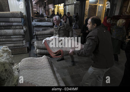 Tehran, Iran. 27th Dec, 2014. December 27, 2014 - Tehran, Iran - Iranian traders carrying a hand woven carpet at a carpet bazaar in Tehran's Grand Bazaar. Morteza Nikoubazl/ZUMAPRESS © Morteza Nikoubazl/ZUMA Wire/Alamy Live News Stock Photo