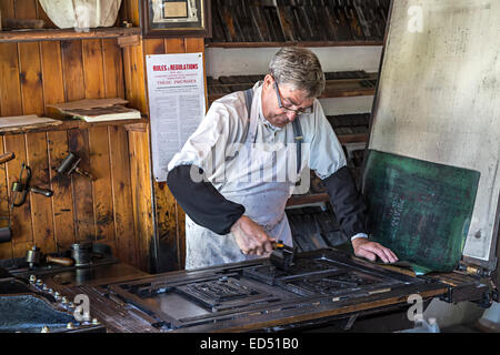 Printer inking typeset text on a printing press, Blists Hill Victorian town, Ironbridge, Shropshire, England, UK Stock Photo
