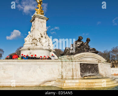 LONDON THE VICTORIA MEMORIAL AT BUCKINGHAM PALACE WITH VISITORS IN RED FATHER CHRISTMAS HATS Stock Photo