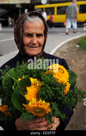 A woman selling freshly picked flowers outside the Zeleni Venac green market in central Belgrade, Serbia. Stock Photo