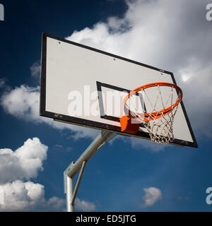 Basketball hoop against  lovely blue summer sky with some fluffy white clouds Stock Photo