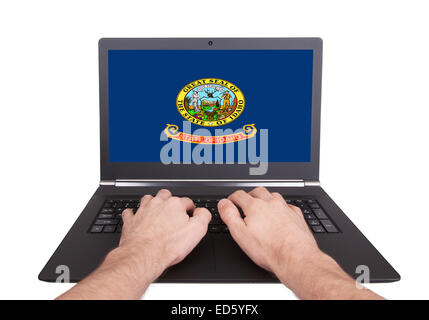 Hands working on laptop showing on the screen the flag of Idaho Stock Photo