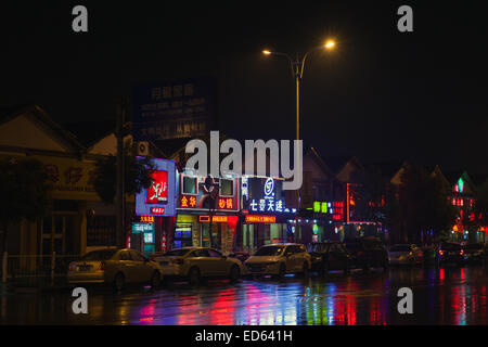 Hangzhou, China - December 3, 2014: Colorful Chinese neon advertising with reflections on wet road. Night street view Stock Photo