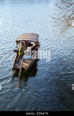 Hangzhou, China - December 5, 2014: Traditional Chinese wooden recreation boat with boatman and passengers floats on the West La Stock Photo