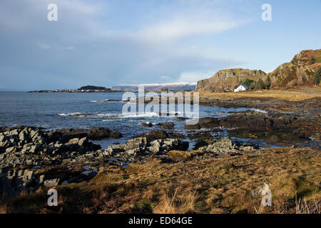 View of incoming tide and breakers on the rocky foreshore looking towards Ellenabeich on a brisk winter day in Scotland Stock Photo