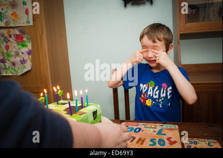 Boy closing eyes for birthday cake surprise Stock Photo