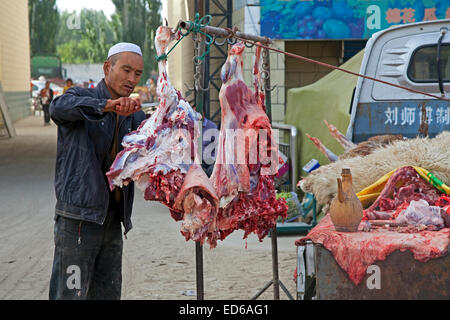 Butcher cutting meat from his pickup truck in the village Waxxari, oasis town in the Taklamakan Desert, Xinjiang Province, China Stock Photo