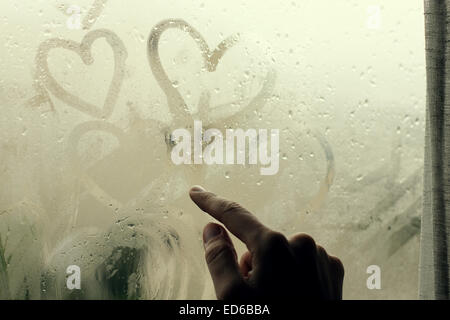 woman drawing heart on wet window Stock Photo