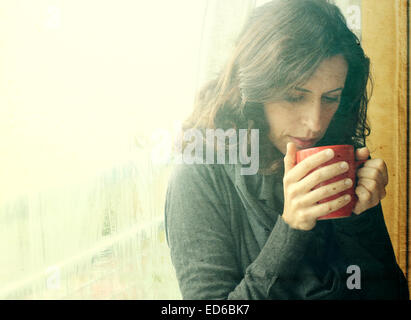 Beautiful young woman enjoying cup of coffee. Retro vintage instagram filter. Stock Photo