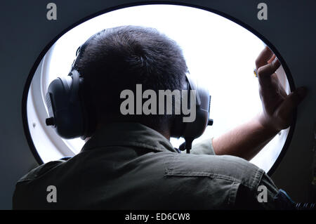 Surabaya, Indonesia. 29th Dec, 2014. A member of the Indonesian military looks out a window during a search-and-rescue operation for the missing AirAsia flight QZ8501 on Monday. © Jeff Aries/ZUMA Wire/Alamy Live News Stock Photo