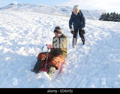 Lifestyle shot of active senior couple on sledge having fun in the snow in Bilsdale, North Yorkshire Stock Photo