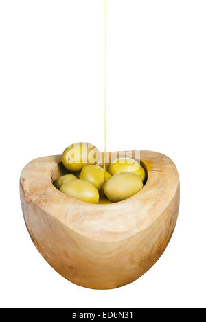 olive oil trickles on green olives in wooden bowl close up isolated on white background Stock Photo