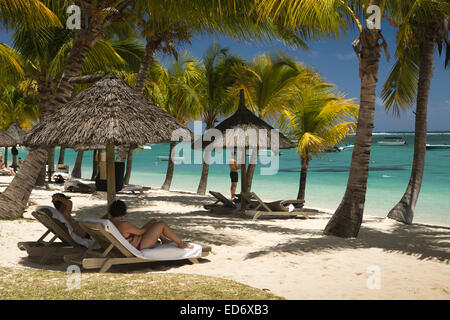 Mauritius, Le Morne, Lux Le Morne hotel beach, people under shady parasols on sea shore Stock Photo