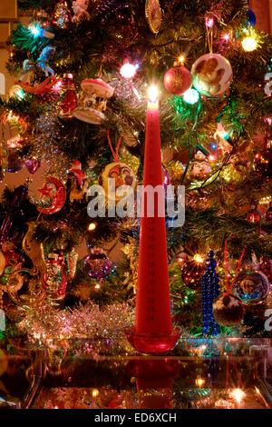 traditional lighted advent candle in front of decorated tree marking the countdown to christmas Stock Photo