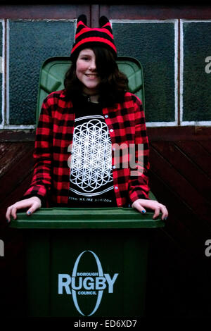 laughing young girl poses whilst playing in a wheelie bin Stock Photo