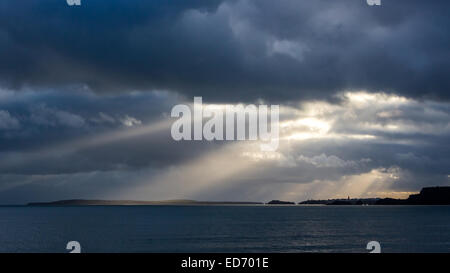 Crepuscular sun rays shine down onto Tenby, Tenby Harbour and Caldey Island on the Pembrokeshire coast. Photographed from Amroth Stock Photo