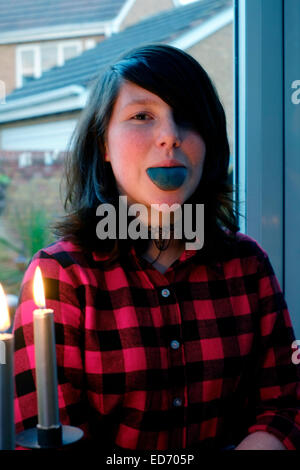 twelve year old girl sticking out her tongue which is dark blue from eating sweets Stock Photo