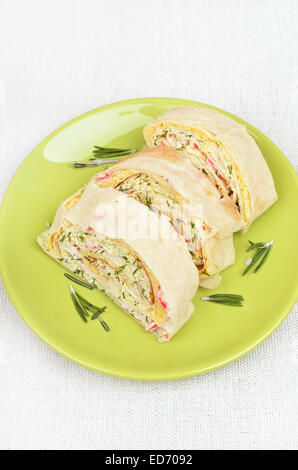 Lavash rolls with crab meat, cheese, eggs and herbs on green plate, top view Stock Photo