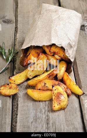 French fries potato wedges in paper bag on rustic table Stock Photo