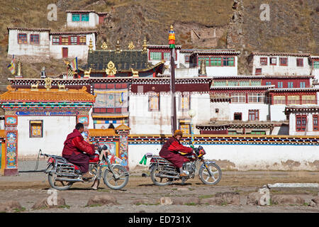 Two young Tibetan monks riding motorbikes in front of monastery between Sershu Dzong and Sershu / Serxu, Sichuan Province, China Stock Photo