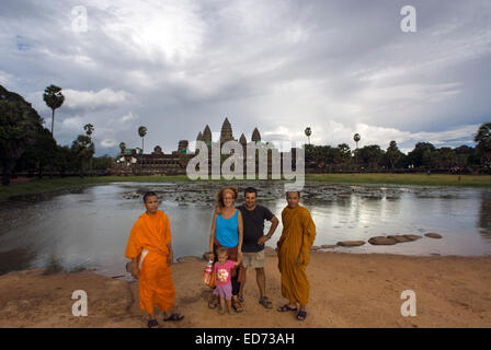 Family with chidren taken pictures with monks on the outside of the Temple of Angkor Wat. The plan of Angkor Wat is difficult to Stock Photo