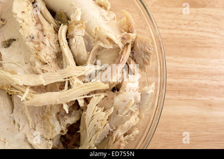 Close view of a glass bowl filled with large chunks of turkey on a wood counter top. Stock Photo