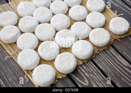 Set of small heads of young goat cheese crottin  lying on wooden boards Stock Photo